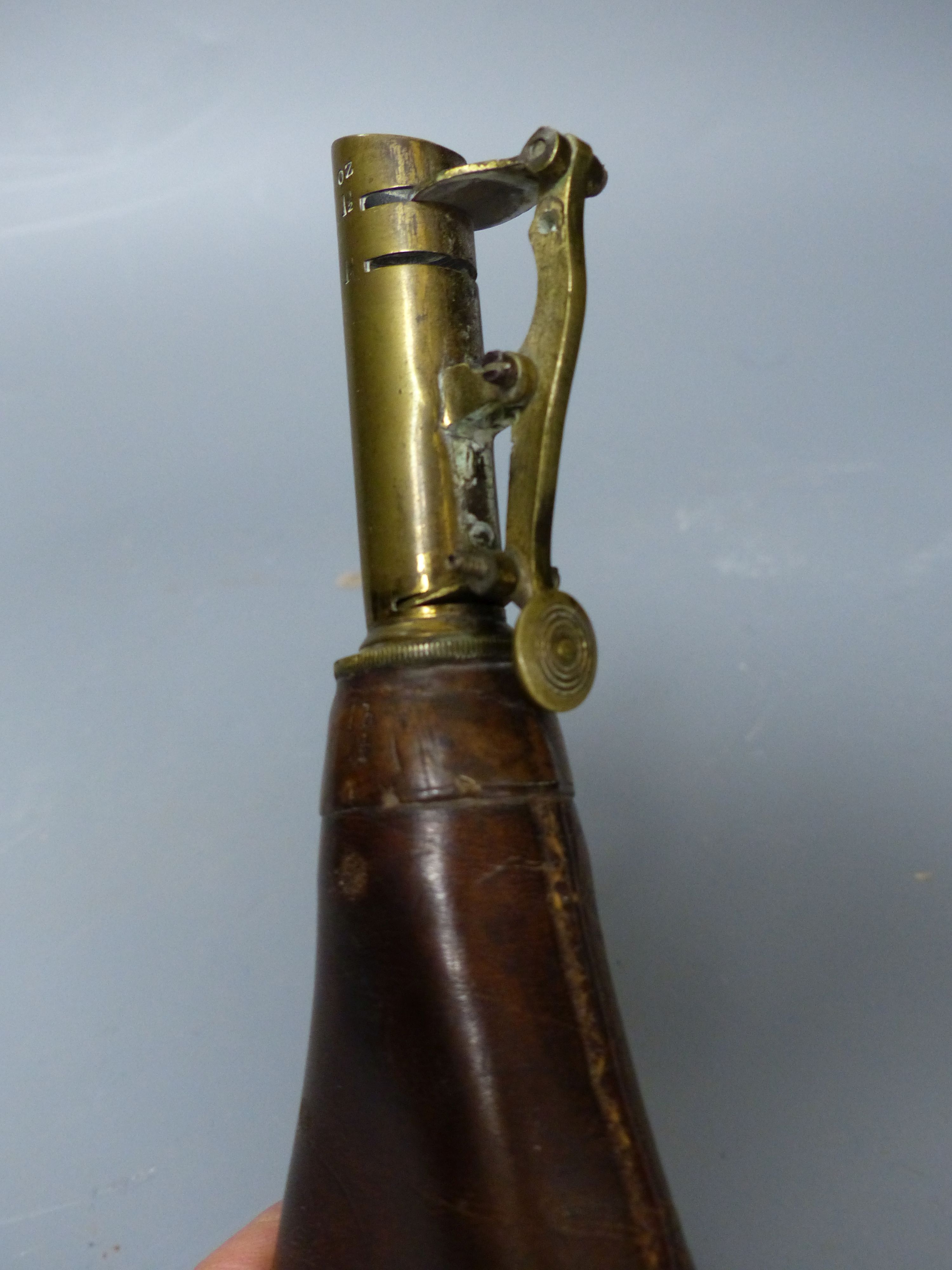 A 19th century brown leather and brass powder flask, overall length 23cm